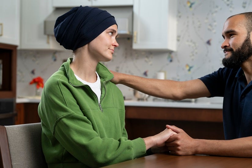 A female patient is comforted by a male healthcare worker.