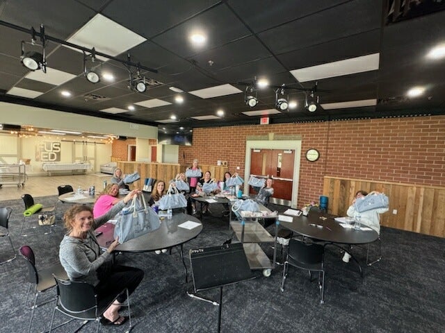 A group of women show off their handbags at a recent TMOAA retreat.