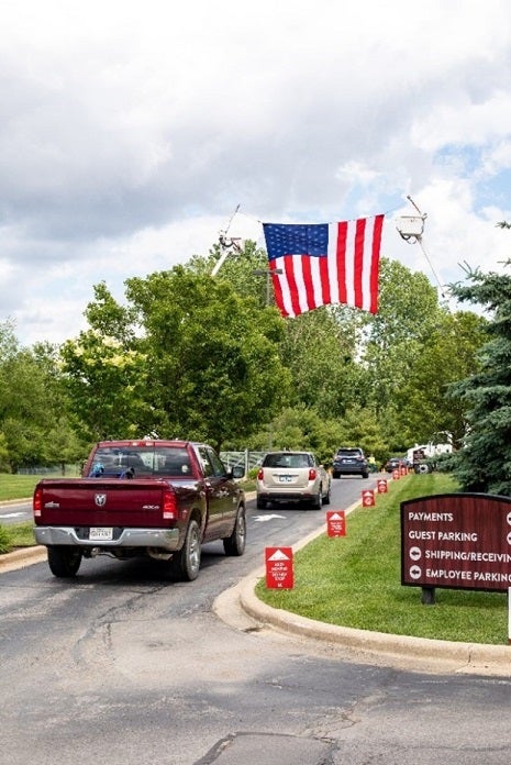 KREMC members drive up to the facility in a line. A large American flag waves proudly.
