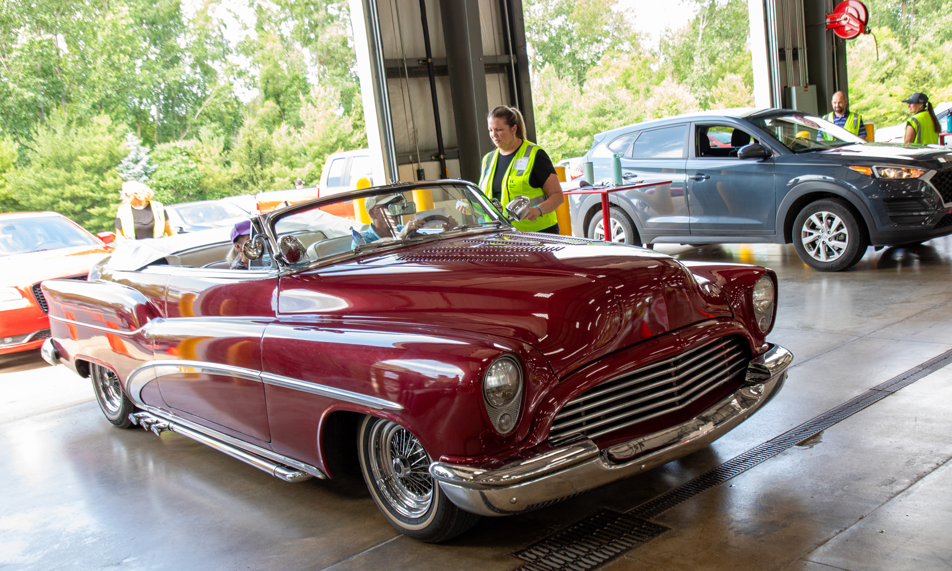 KREMC's Rachel Miller speaks with two co-op members as they drive through the annual meeting in a red convertible.