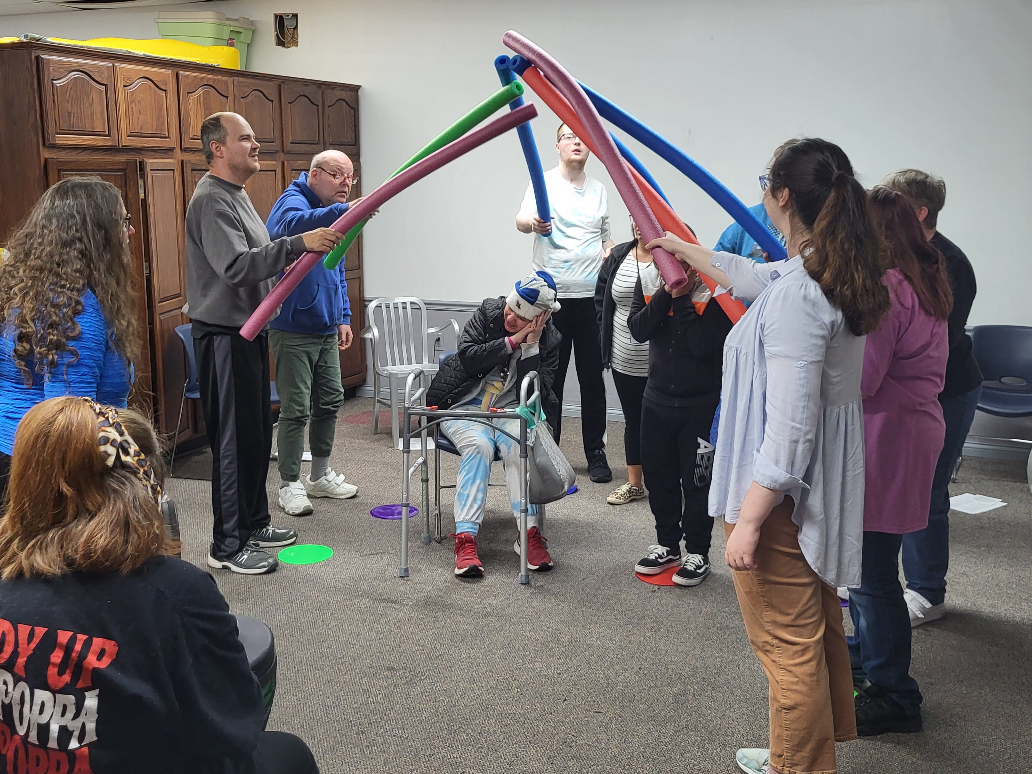 Cardinal Services clients acting out a scene with pool noodles