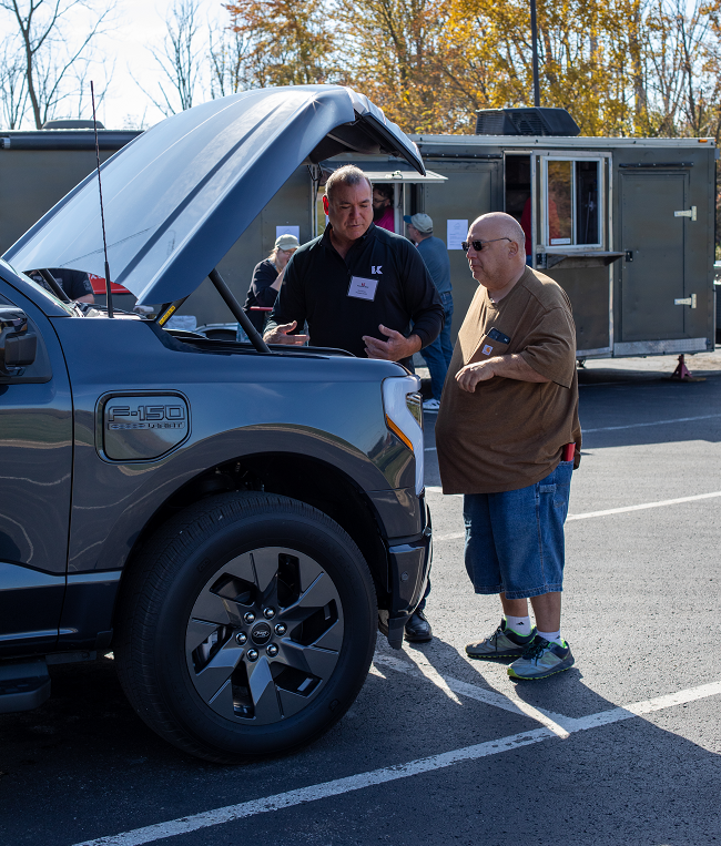 Kurt Carver looks under the hood of an EV with a KREMC member.