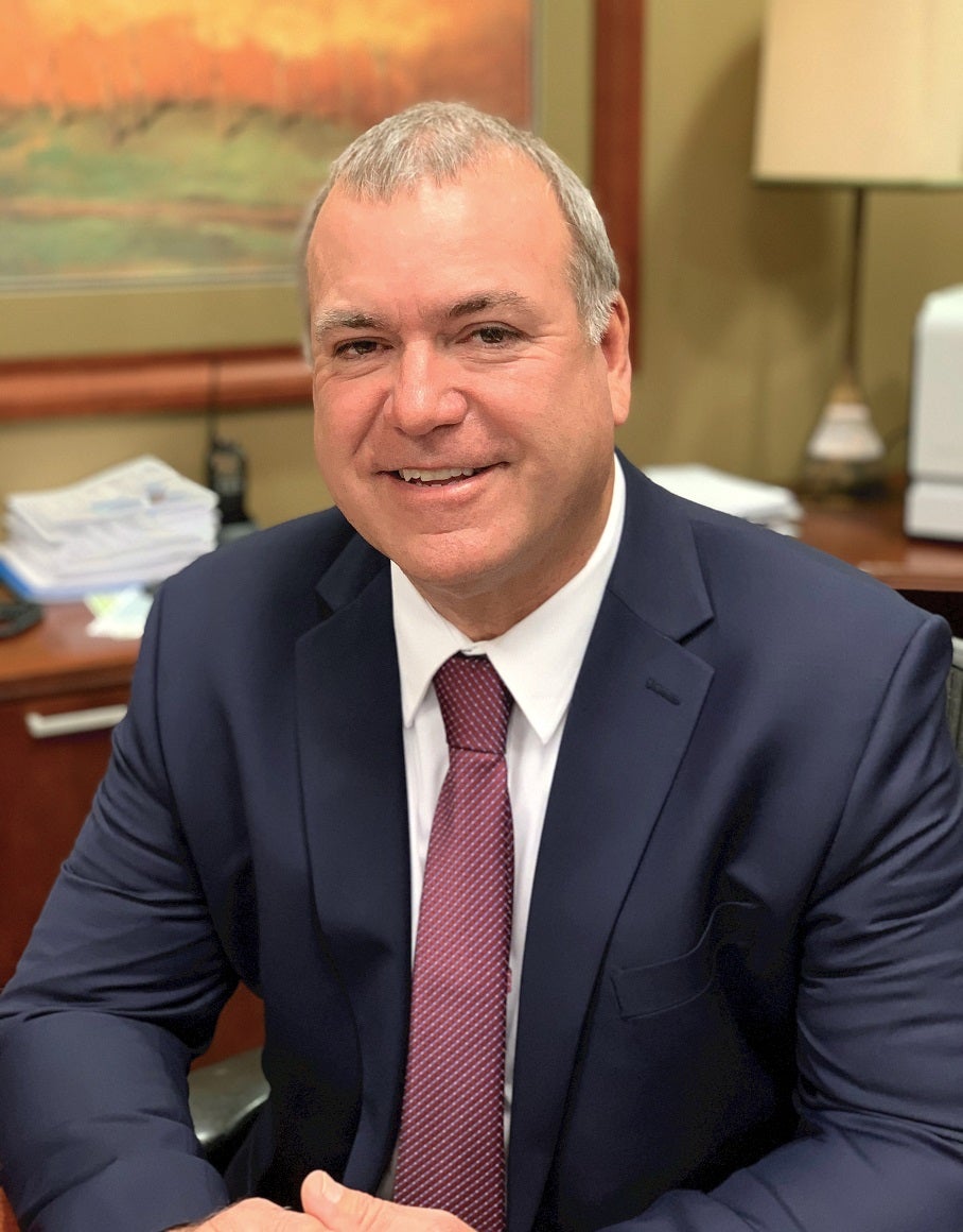 Photograph shows Kosciusko REMC CEO Kurt Carver seated at a desk.