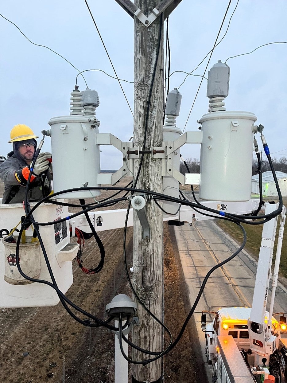 A lineman works at the top of a utility pole.