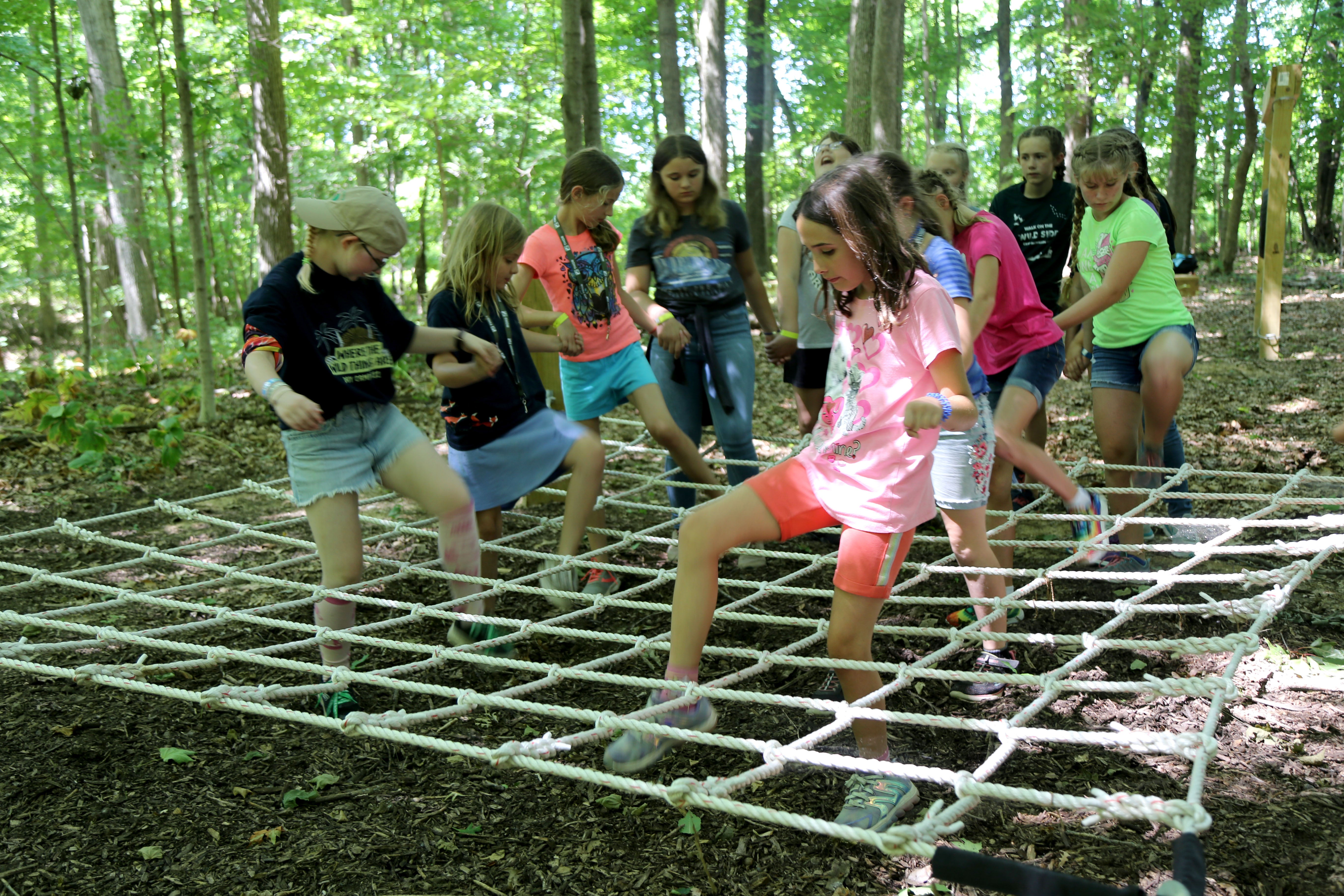 Girl scouts walk through low ropes challenge together