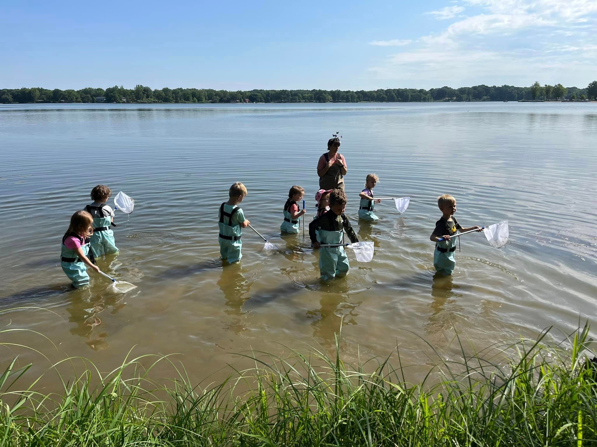 Presby students in waders, walking through lake