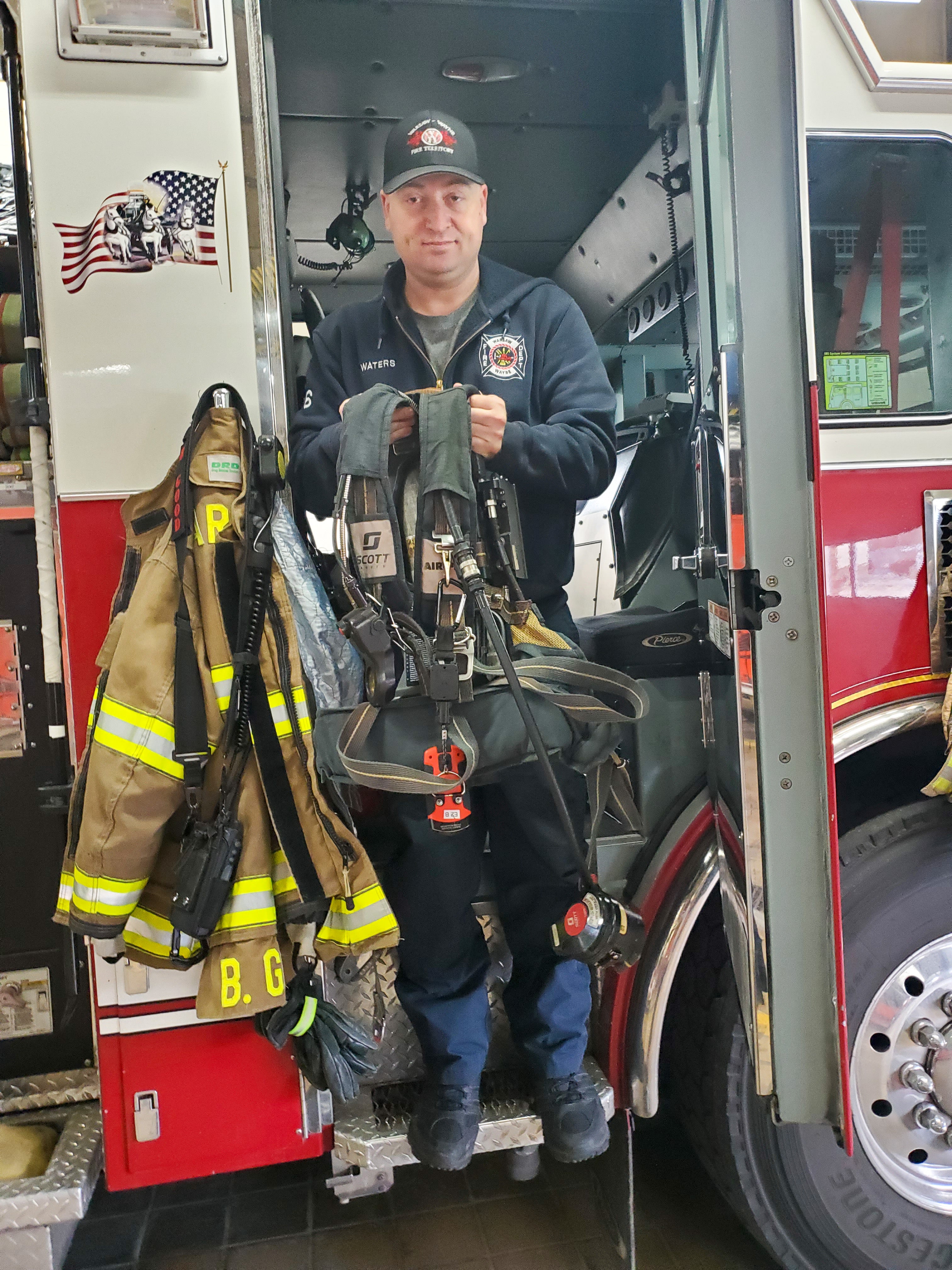 Warsaw-Wayne Fire Territory firefighter Miles stands in the door of a firetruck.