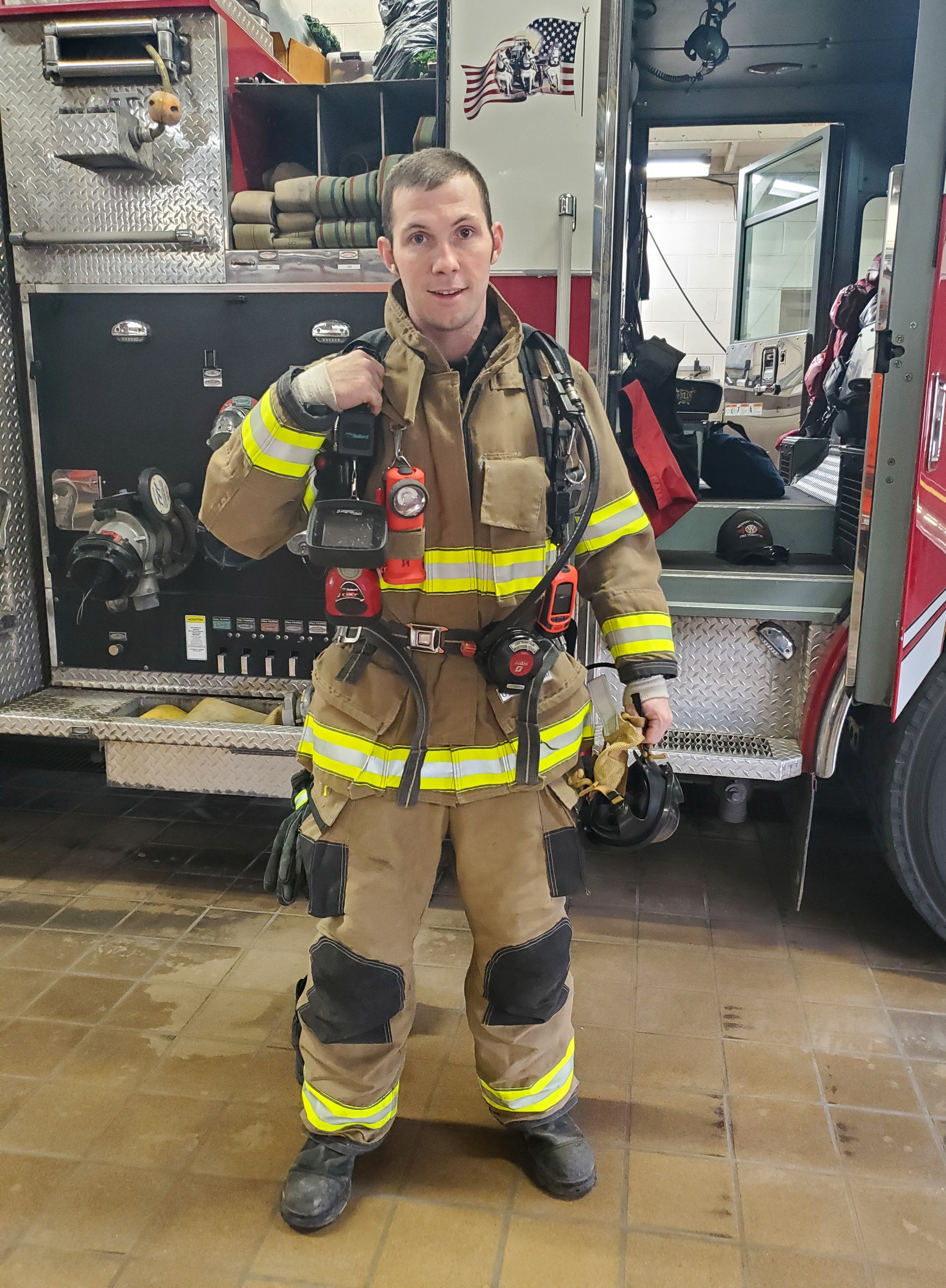 Firefighter Brice Good demonstrates the gear the firefighters typically put on for call.