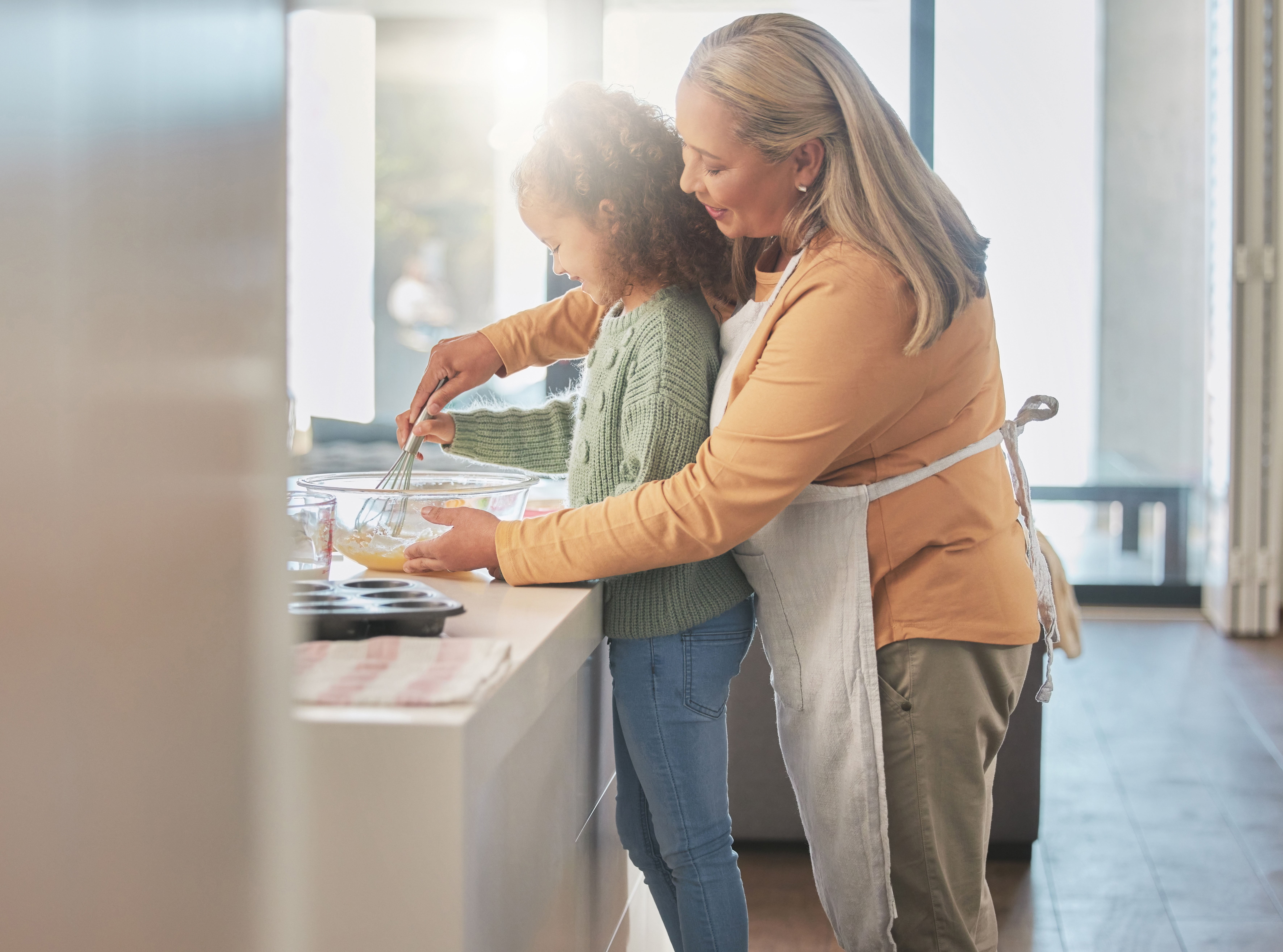 Grandmother and granddaughter mixing cake ingredients together