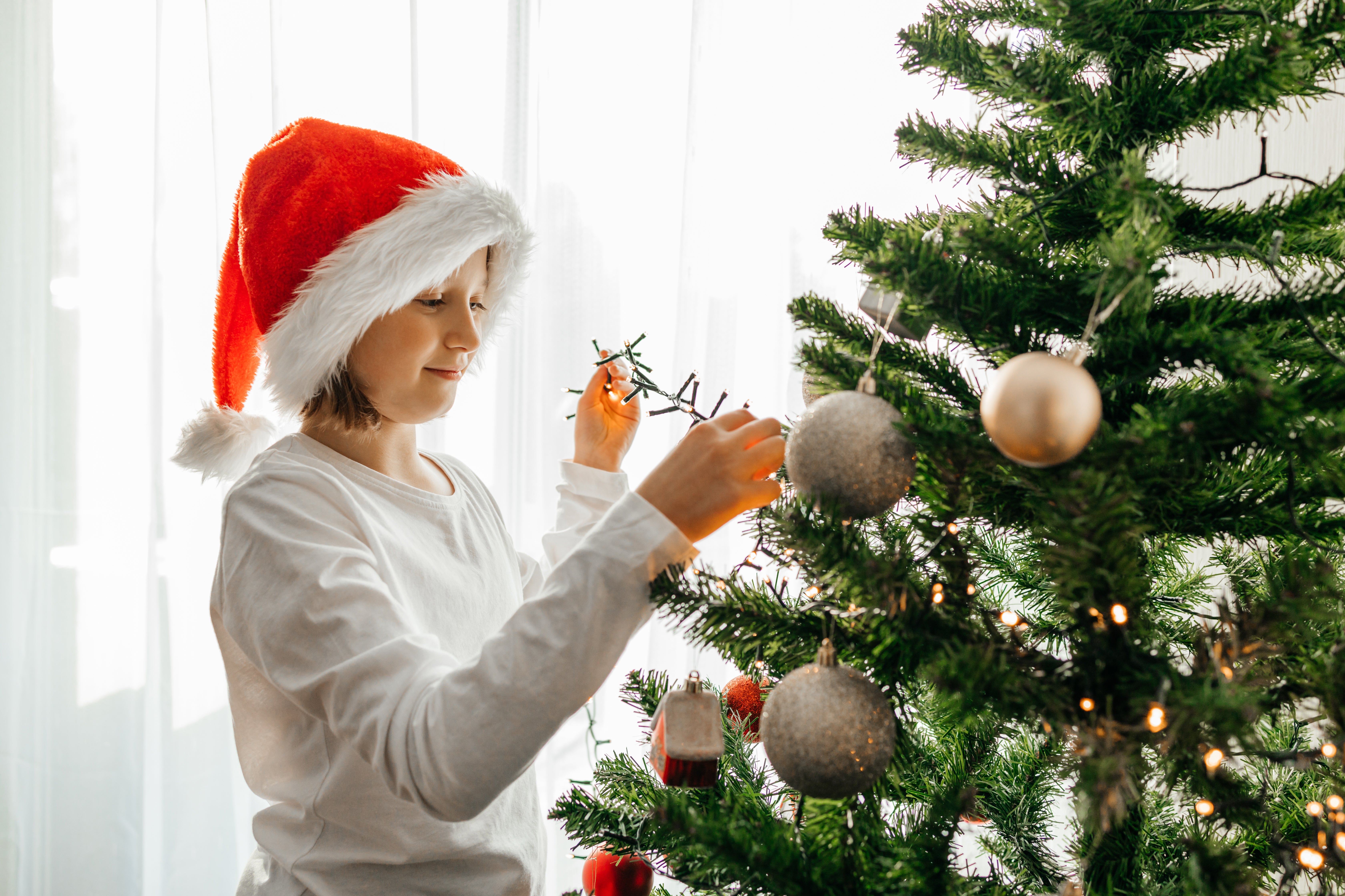 Young girl string LED lights on Christmas tree