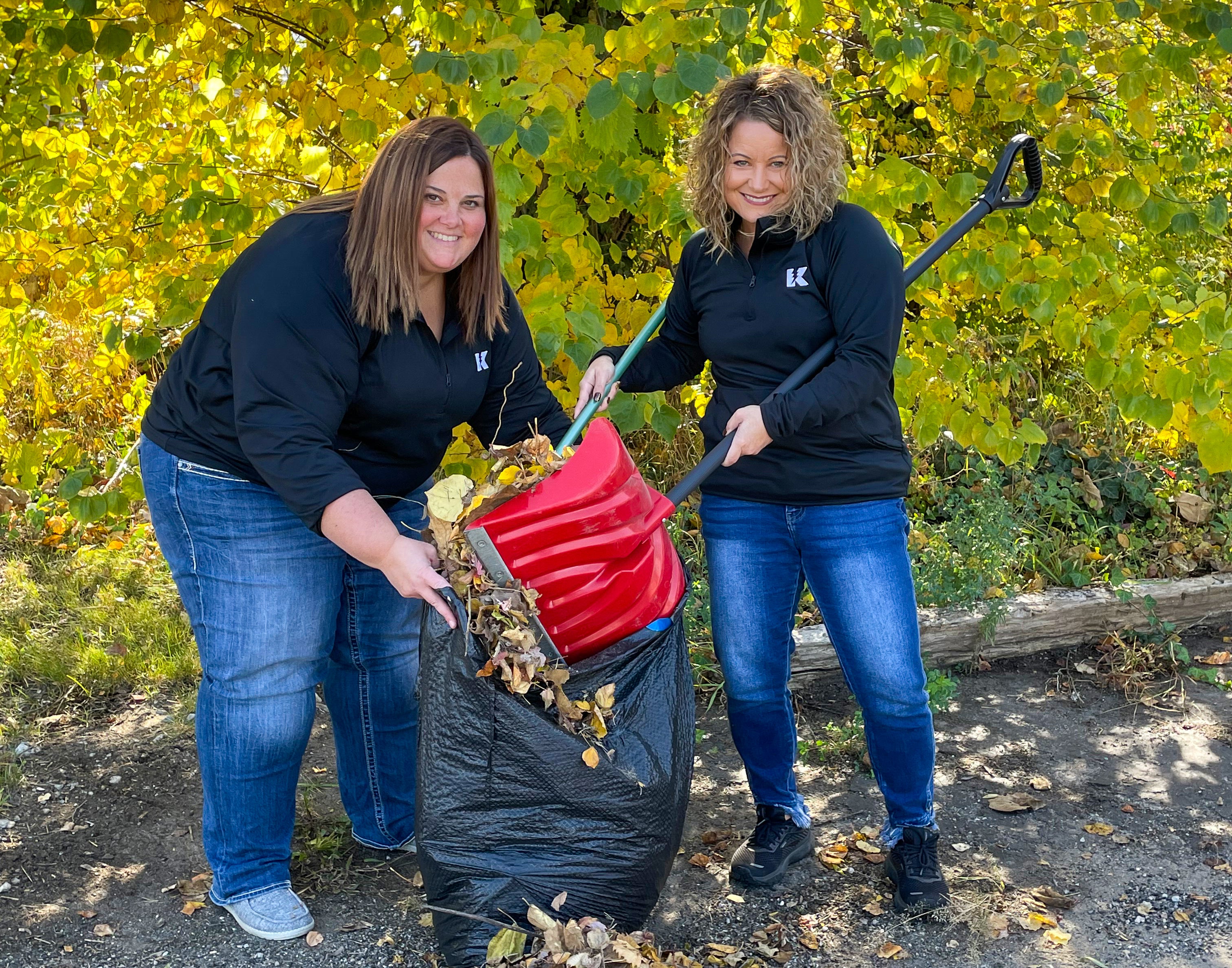 Two KREMC employees raking leaves together