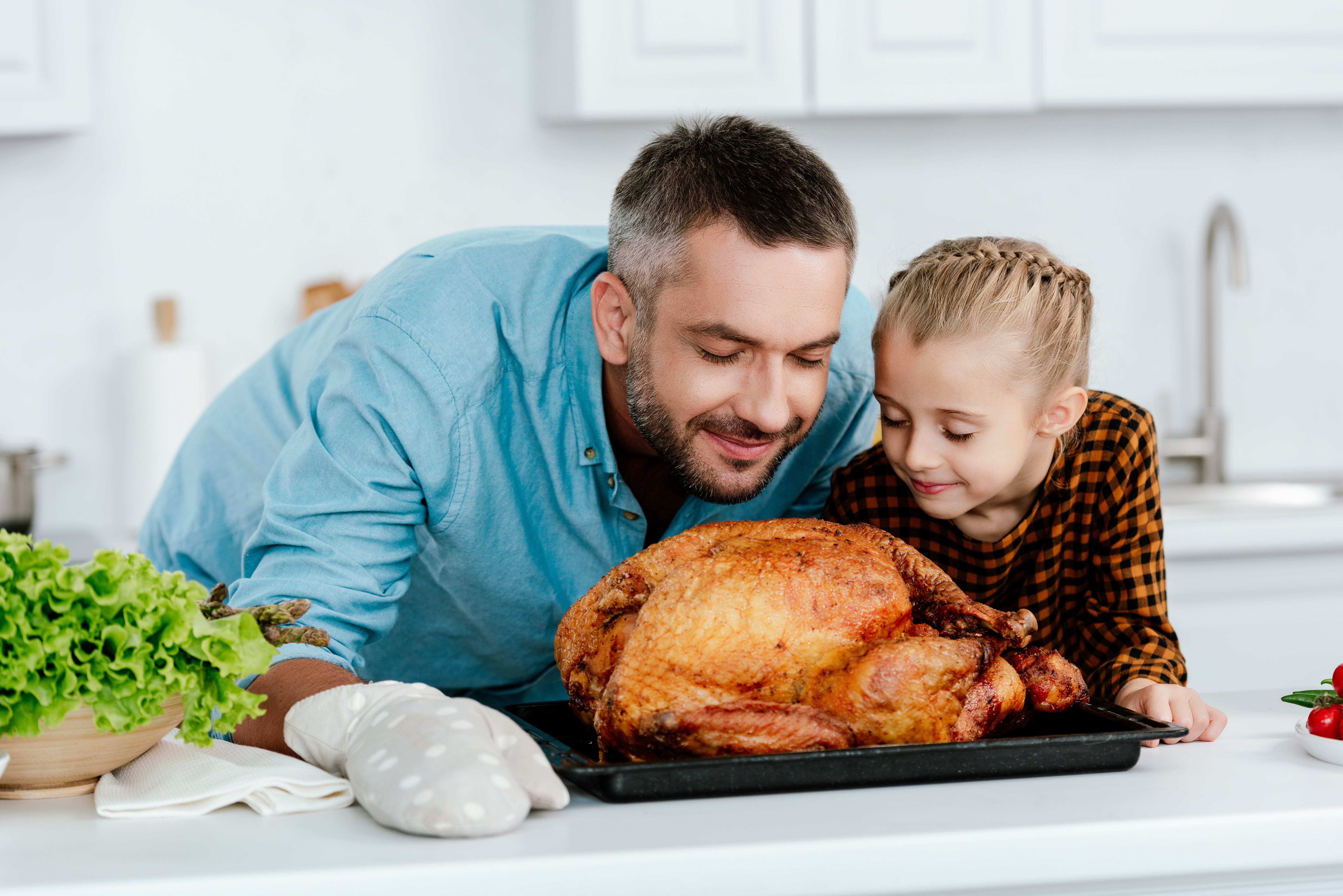 Happy father and daughter smelling cooked turkey