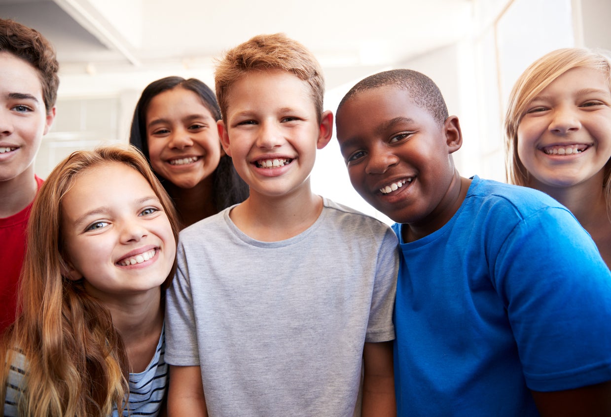 A group of middle school students smile at the camera