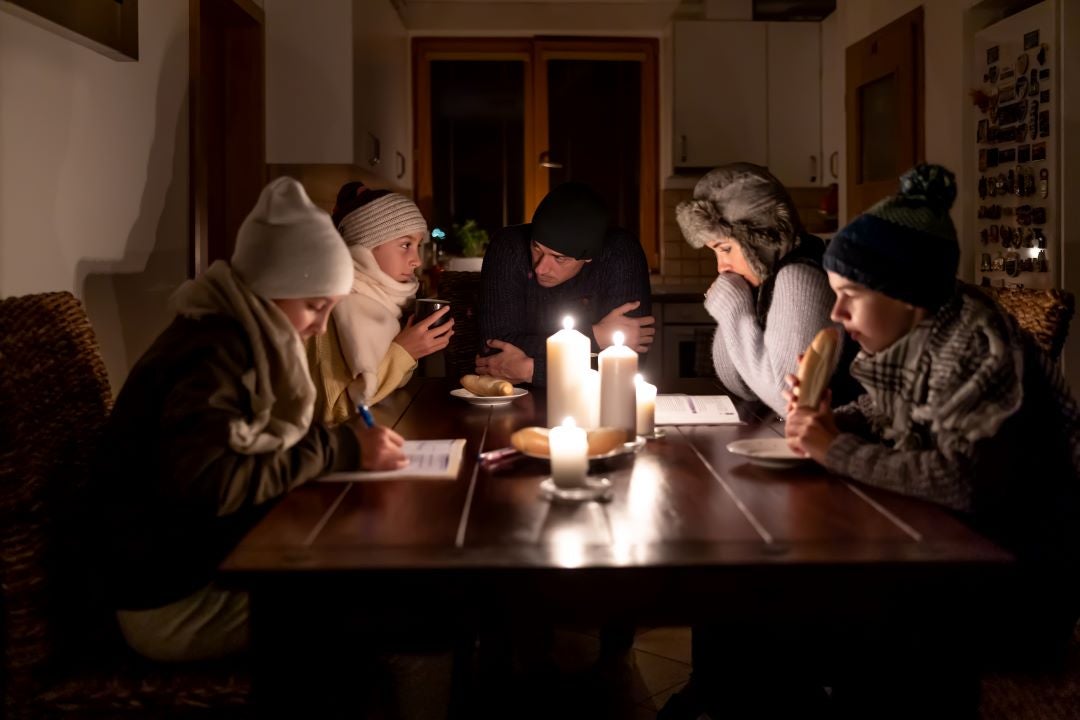 Family around table in dark with candles