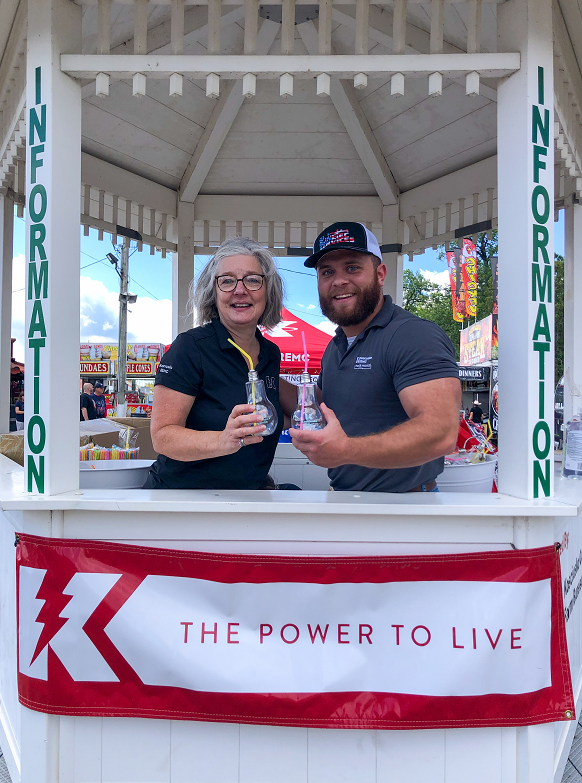 Two KREMC employees stand in a gazebo at the 2022 Warsaw County Fair
