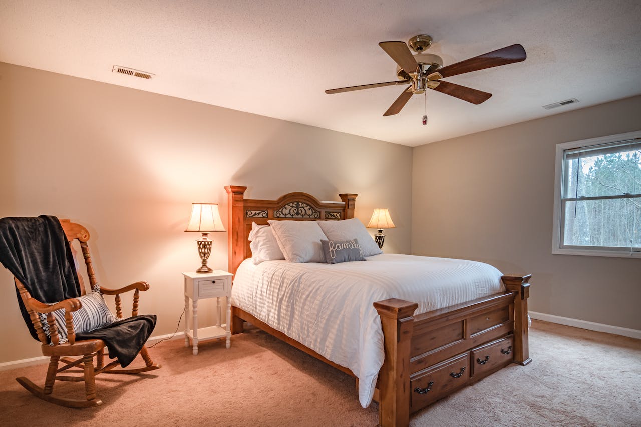 A cozy bedroom is pictured with a ceiling fan above the bed.