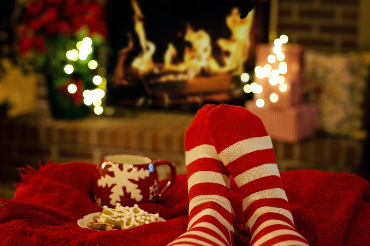 A person's feet in red and white socks propped up in front of a cozy fire.