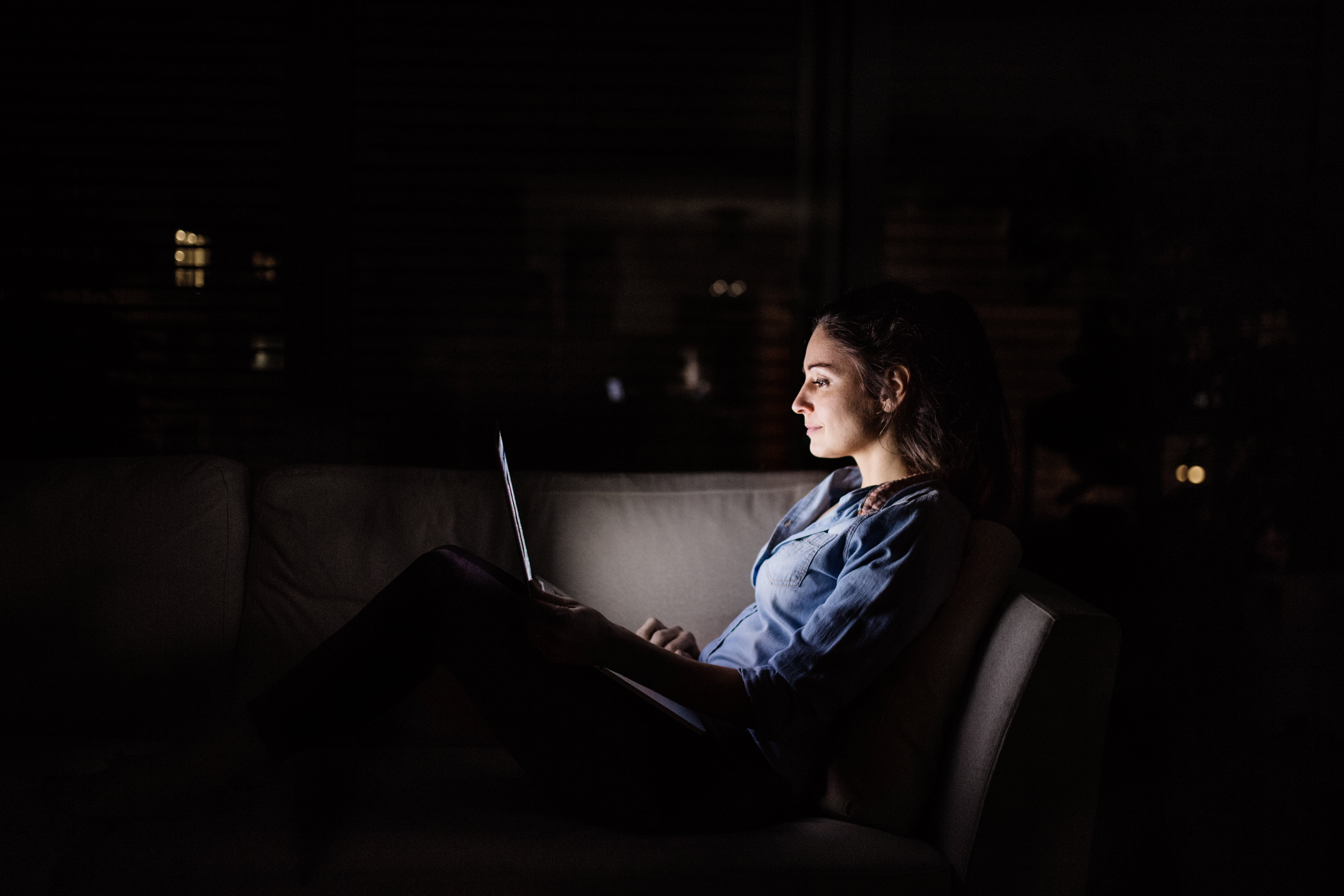 Woman reporting outage on laptop in the dark