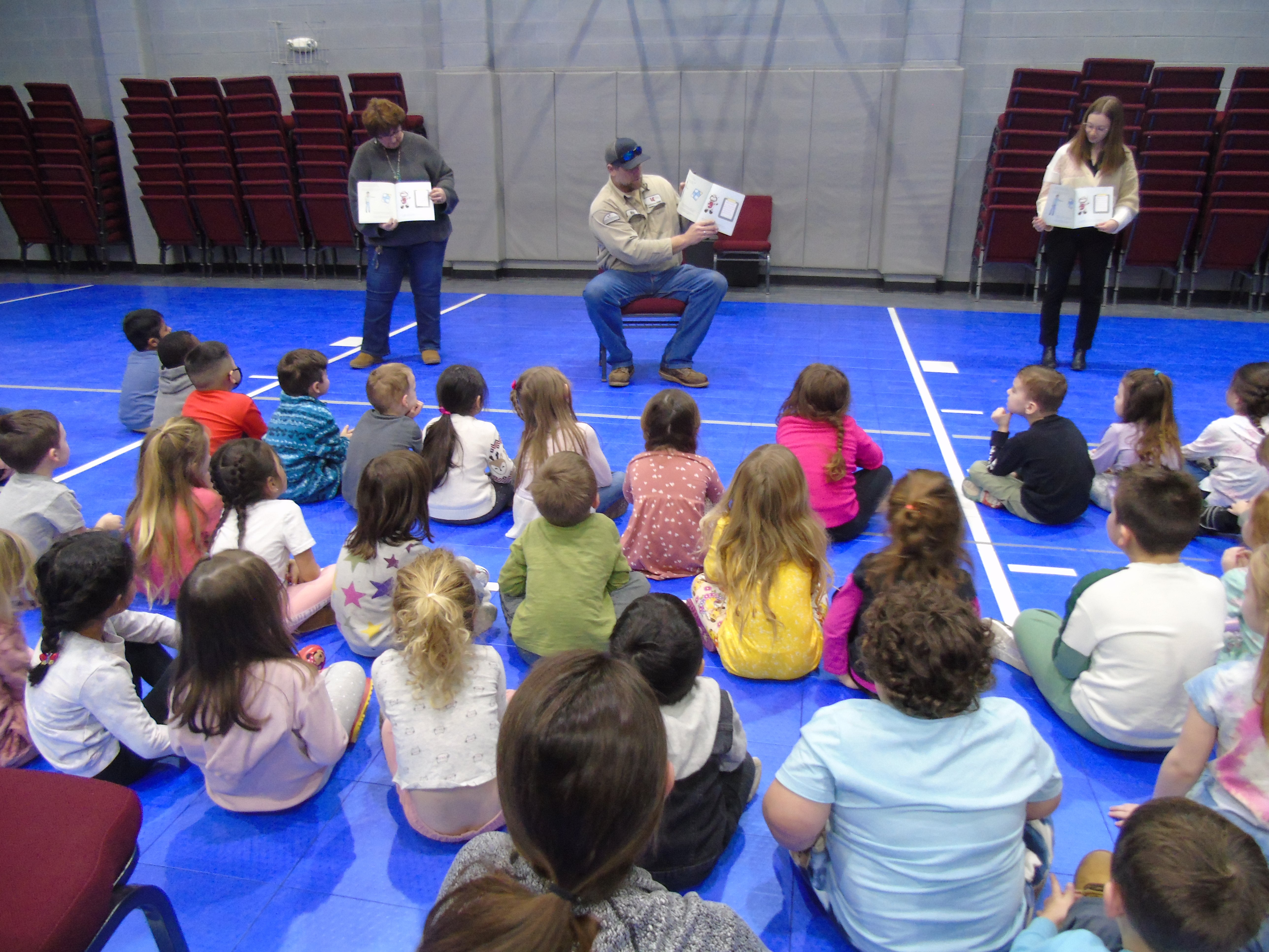 Lineman reading picture book to preschoolers in Presby gym