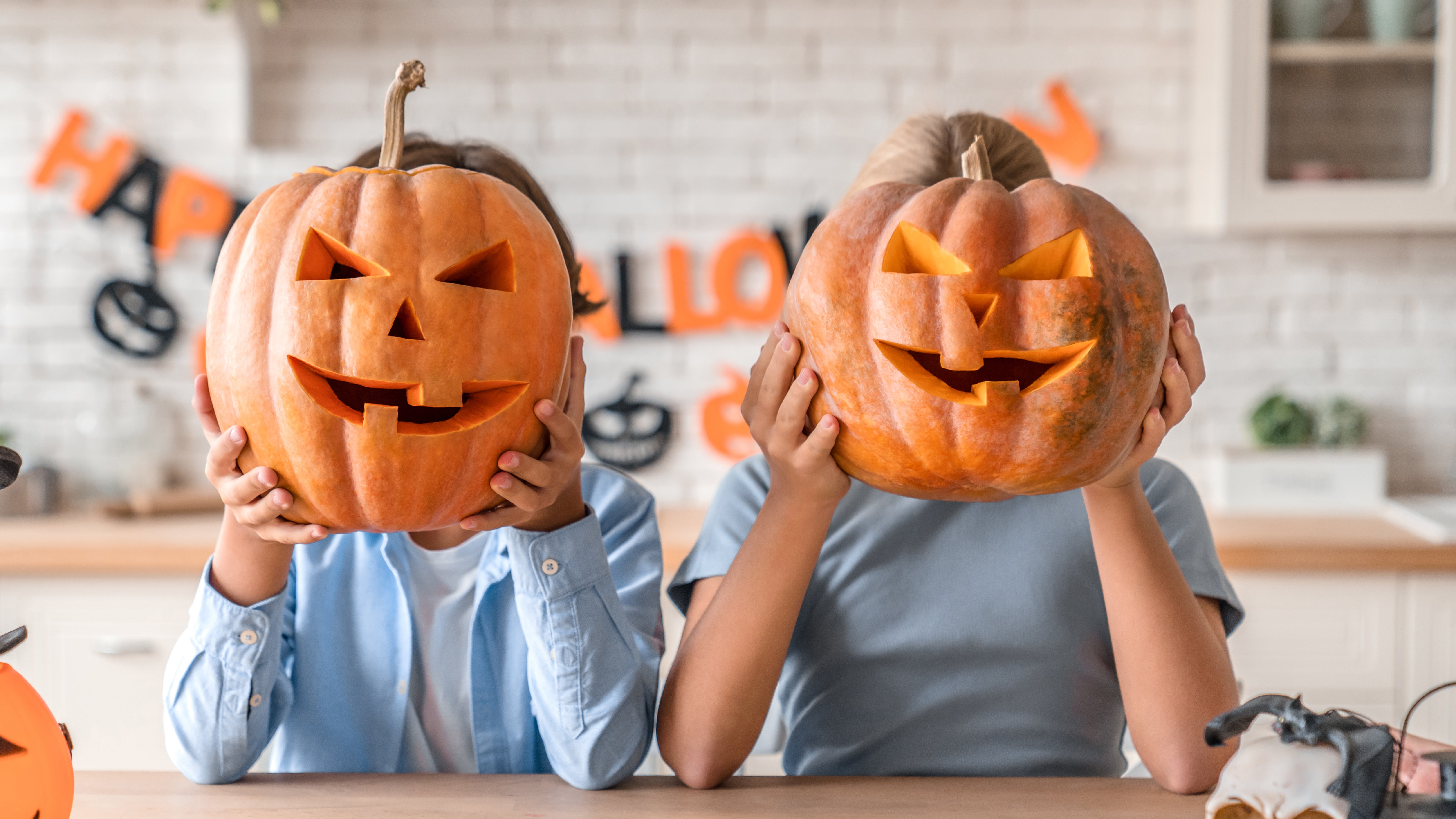 Two kids holding up carved pumpkins